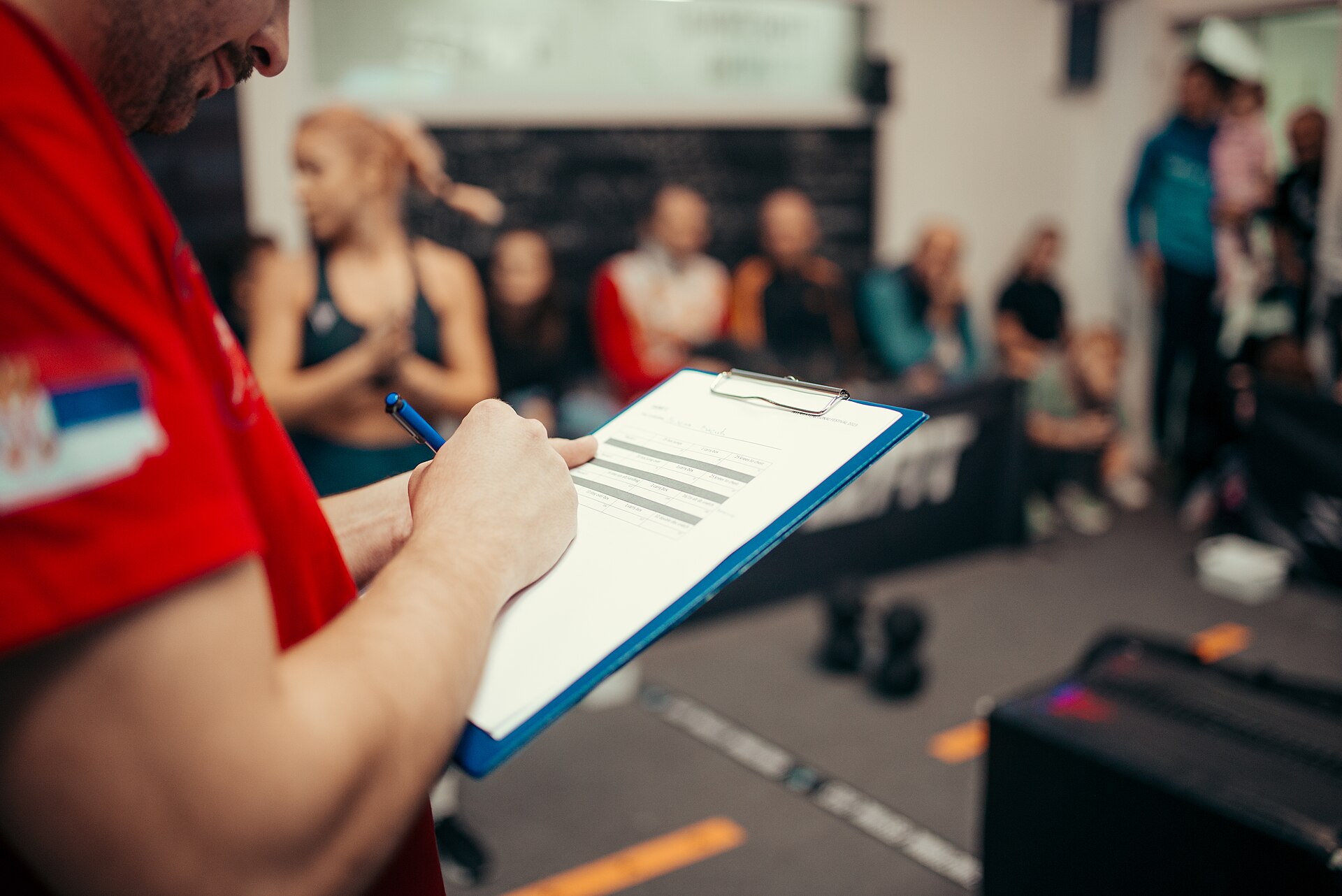 A coach writing down an athlete's lift on a clipboard