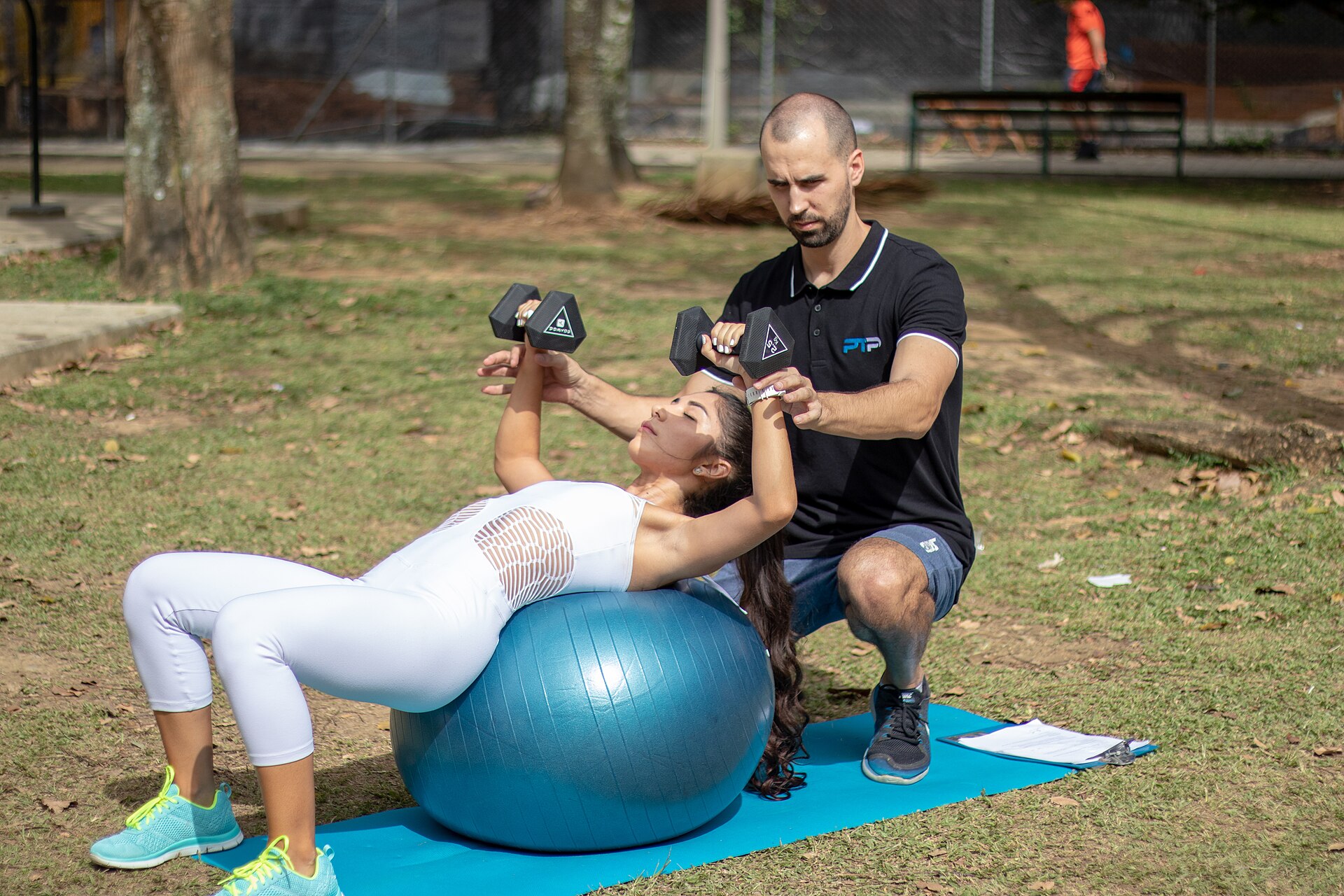 A coach guiding a client's dumbbell press
